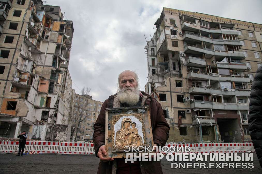 Дедушка с иконой напротив разрушенного дома на Победе